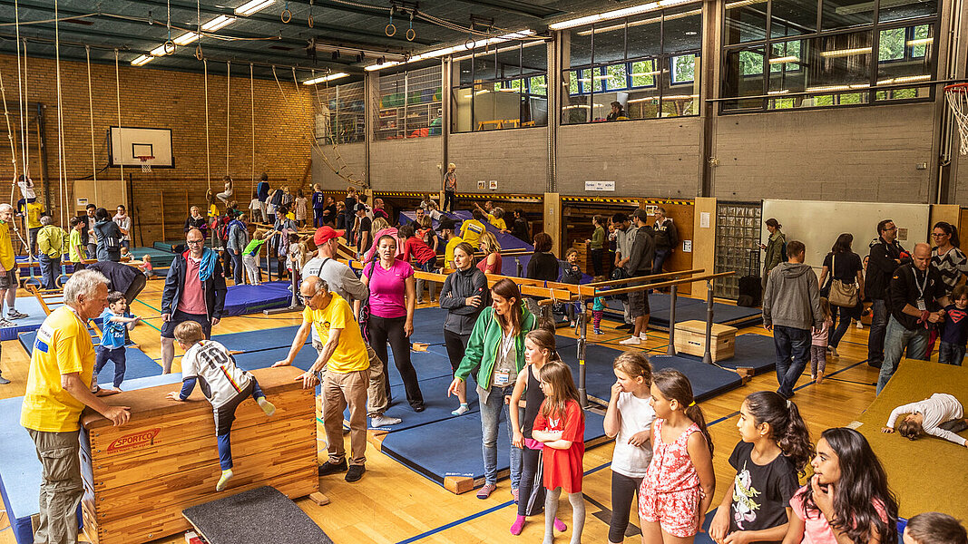 Kinder beim Abeteuerturnen in einer Sporthalle.