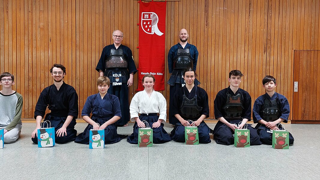 Das Kendo-Team das Kendo Dojo Köln mit Kendo-Ausrüstung gruppiert in einer Sporthalle.