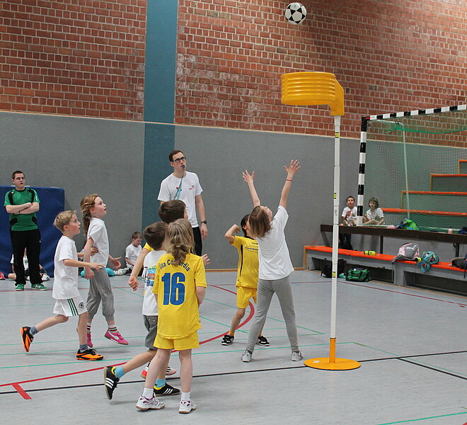 Kinder spielen Korfball in einer Halle.