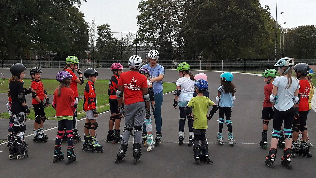 Eine Gruppe von Kindern macht sich mit Helmen und Inlineskates bereit für das Training.